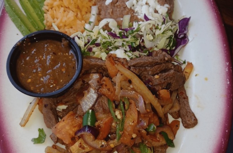 Steak strips with peppers and onions, rice, beans and a cup of salsa.