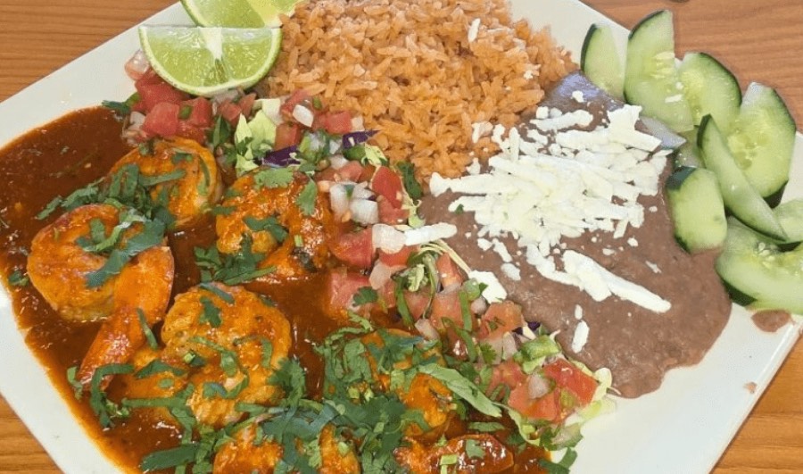 Shrimp in red chile sauce with rice, refried beans, queso fresco and cucumber.
