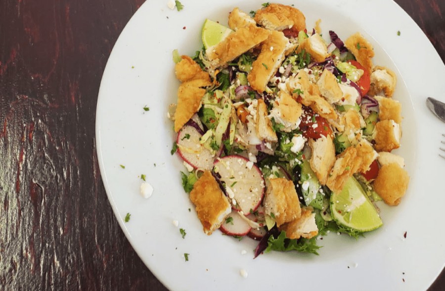 A salad of mixed greens topped with crispy chicken.